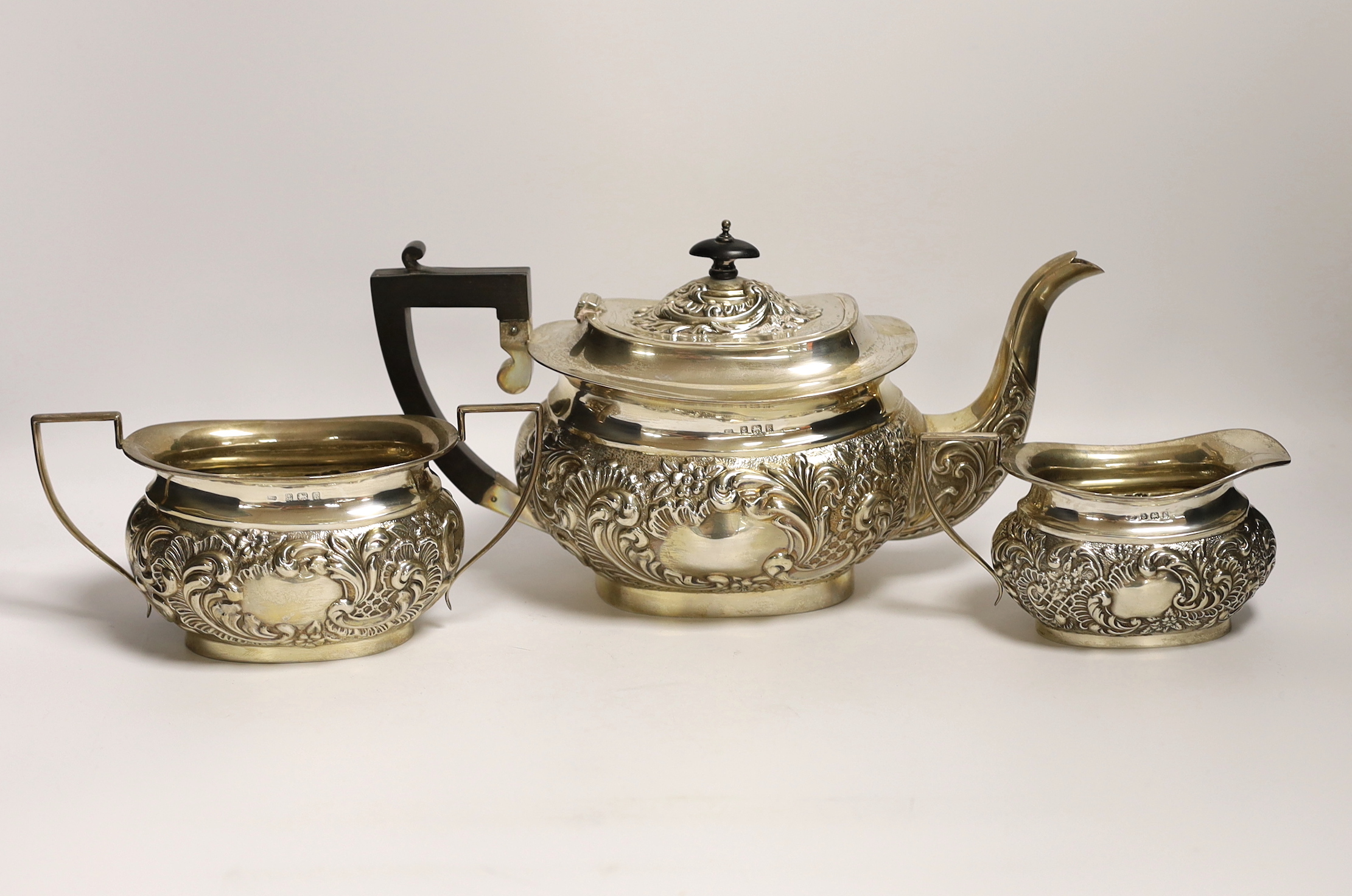 An Edwardian embossed silver three piece tea set, William Devonport, Birmingham, 1909